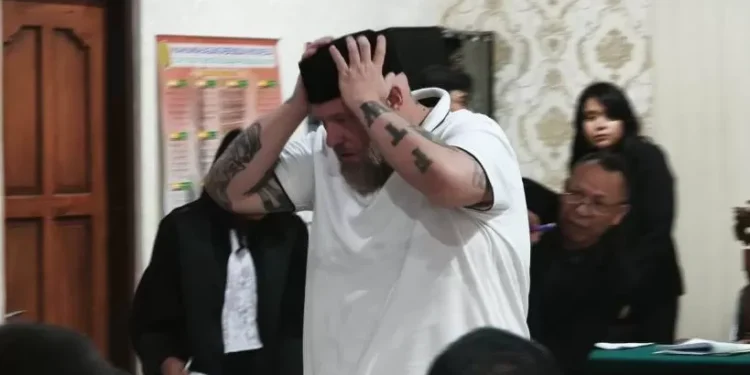 Daniel Domalski wears a peci (traditional Indonesian cap) after the verdict hearing at the Denpasar District Court on Tuesday (16/12).