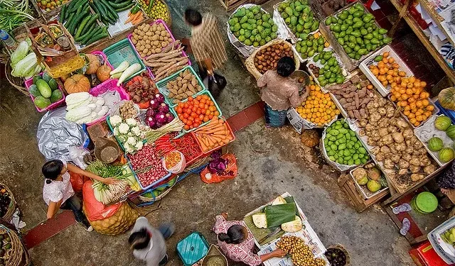 Buying and selling activities in Bali's traditional markets, with traders and buyers interacting among food commodities, reflect the dynamics of people's daily consumption.
