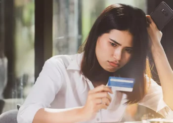 Photo of an Asian woman looking confused while holding her credit card (Source: Freepik)