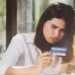 Photo of an Asian woman looking confused while holding her credit card (Source: Freepik)
