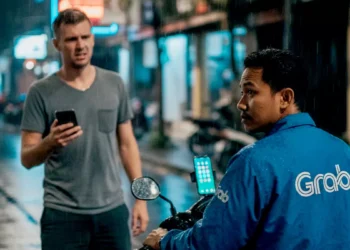 Illustration photo of a drunk tourist in Bali ordering a motorbike taxi service in the rain on a road in Bali (Photo created by AI)