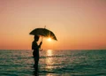 Illustration photo of a foreign tourist enjoying the sunset on a Bali beach while carrying an umbrella during the rainy season (Hey Bali)