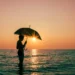Illustration photo of a foreign tourist enjoying the sunset on a Bali beach while carrying an umbrella during the rainy season (Hey Bali)