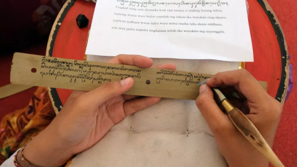 More Than a Script: Bali Mandates Local Aksara, Redefining Cultural Identity in the Global Marketplace 1 Photo of a person writing Balinese script on a palm leaf (Antara/Nyoman Hendra Wibowo)