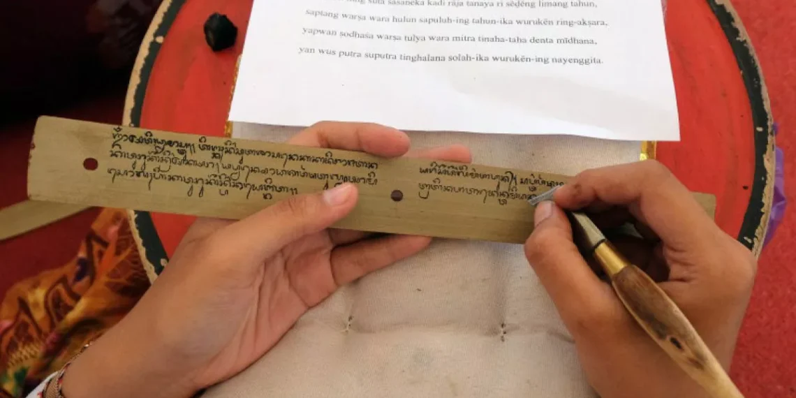 Photo of a person writing Balinese script on a palm leaf (Antara/Nyoman Hendra Wibowo)