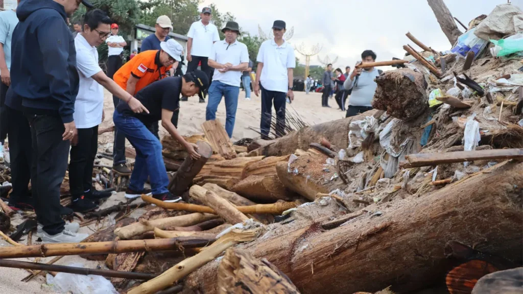 Photo of I Wayan Koster, Governor of Bali (squatting, wearing jeans, black polo shirt and hat) picking up trash, February 6, 2026 (Hey Bali News)