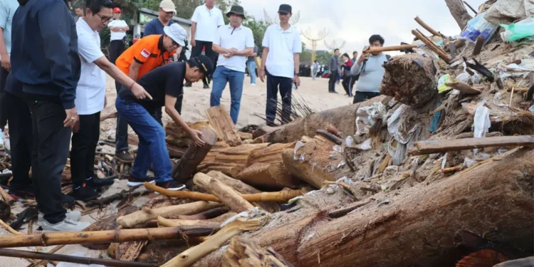 Photo of I Wayan Koster, Governor of Bali (squatting, wearing jeans, black polo shirt and hat) picking up trash, February 6, 2026 (Hey Bali News)