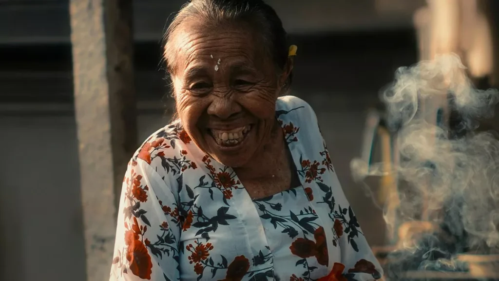 The Finnish Formula for Happiness: A Mirror for Bali's Soul in the Age of Instagram 1 Illustration photo of a grandmother in Bali looking happy smiling (hey bali )