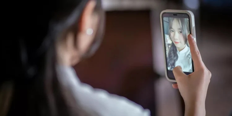 Illustration photo of a woman taking a selfie with a cellphone made by Apple