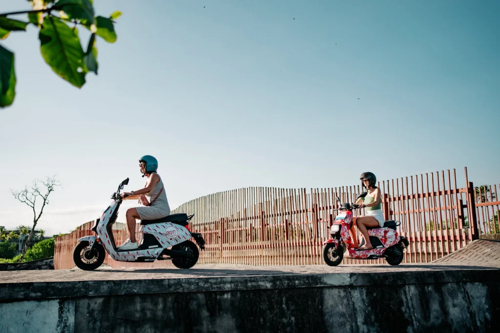 Photo of tourists in Bali riding electric motorbikes and walking to a tourist spot