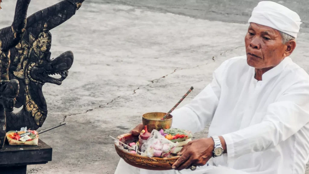 Photo of a Hindu priest in Bali praying in front of a temple (Pexels)