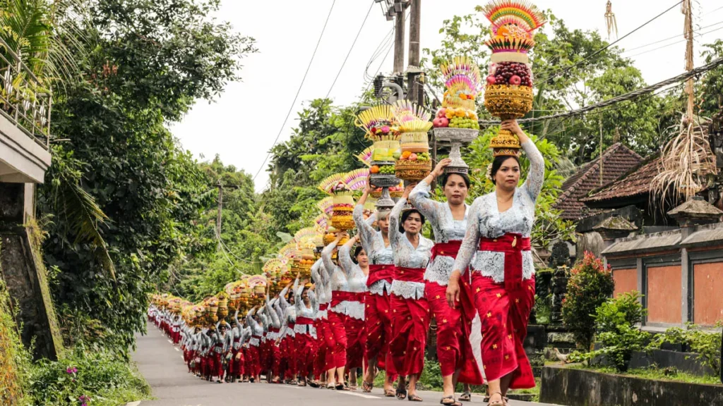 Most Visitors Think Galungan Is One Holiday. Bali's Ancient Texts Say There Are Three. 4 Balinese Hindu women carry colorful ceremonial offerings during a Galungan procession in a traditional village in Bali, Indonesia, celebrating the victory of good over evil.
