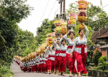 Balinese Hindu women carry colorful ceremonial offerings during a Galungan procession in a traditional village in Bali, Indonesia, celebrating the victory of good over evil.