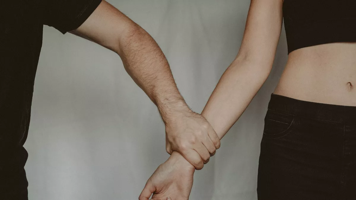 A person's wrist tightly held by another individual, symbolizing emotional manipulation, coercive control, toxic relationships, and psychological abuse.
