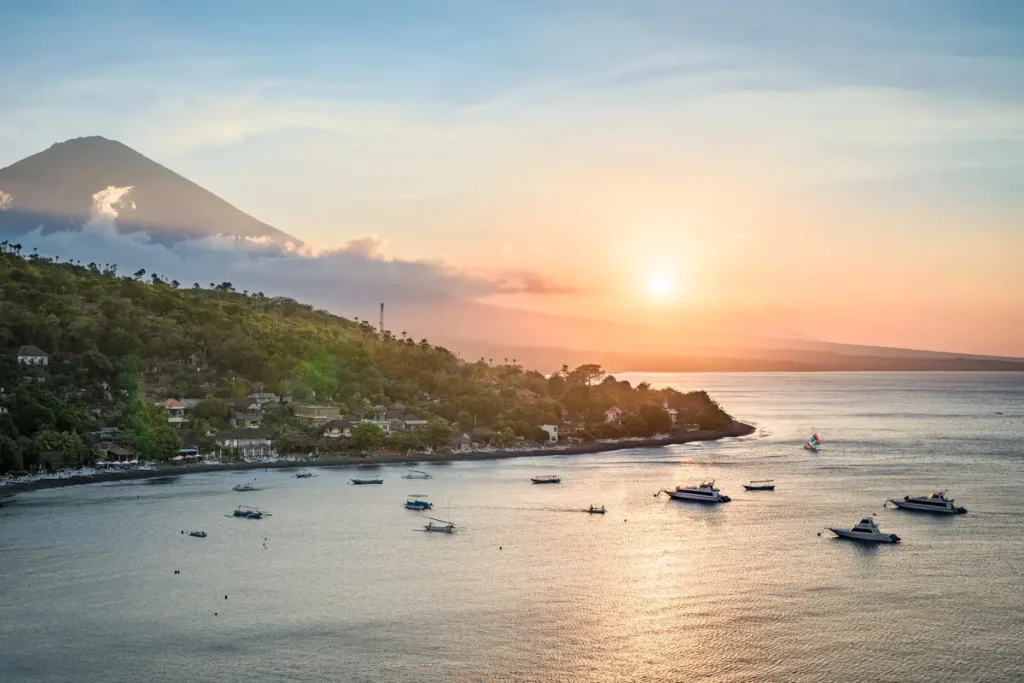 Sunset Point Amed, Bali: 5 Reasons This East Bali Clifftop Deserves a Spot on Your Itinerary 1 A view of the north coast of Bali at sunset—featuring the peak of Mount Agung, forested slopes, and the Java Sea—seen from a hilltop near Amed, Bali, Indonesia. (depositphotos.com/emcamposphoto)