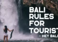 Bali rules for tourists guide featuring a visitor enjoying a waterfall while practicing responsible travel and respecting local customs.