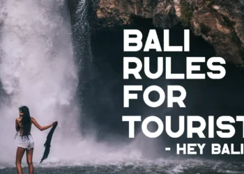 Bali rules for tourists guide featuring a visitor enjoying a waterfall while practicing responsible travel and respecting local customs.