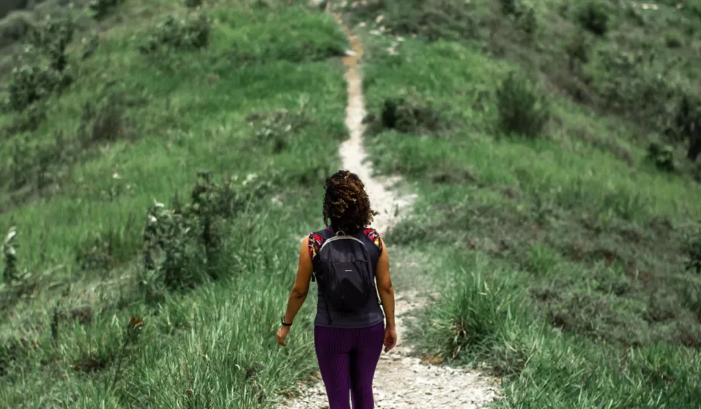 Hiking vs. Trekking: What's the Real Difference, and Which One Is That Mount Batur Sunrise Climb Everyone's Talking About? 38 Solo hiker walking along a scenic trail, illustrating the difference between hiking vs trekking and beginner hiking adventures similar to a Mount Batur sunrise hike in Bali.
