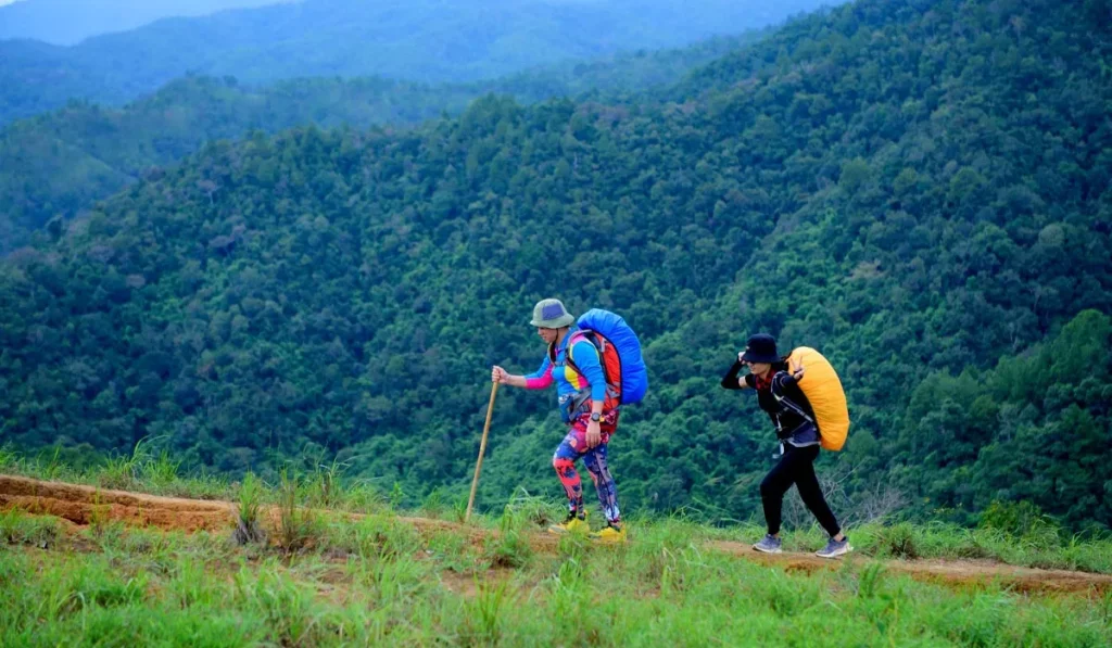 Hiking vs. Trekking: What's the Real Difference, and Which One Is That Mount Batur Sunrise Climb Everyone's Talking About? 40 Two trekkers carrying large backpacks on a mountain trail, demonstrating the difference between trekking and a typical Mount Batur sunrise hike in Bali.
