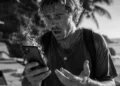 Tourist holding an overheating smartphone while traveling in Bali, illustrating why phones overheat when charging in Bali's tropical heat.