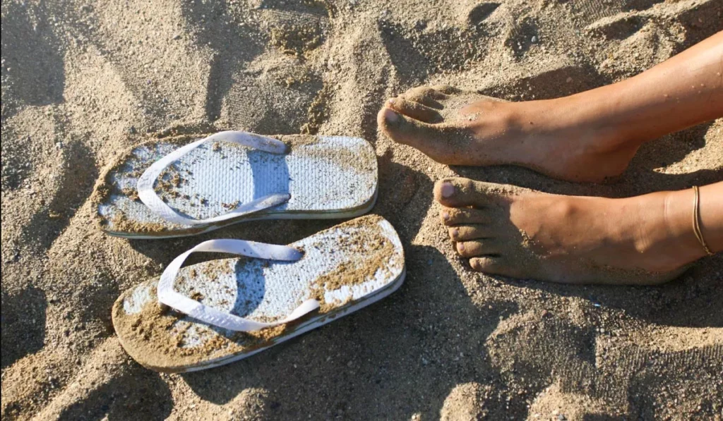 What Shoes Should You Wear in Bali? Sandals, Sneakers or Hiking Boots? 40 Flip-flops and bare feet on a sandy Bali beach, ideal sandals for relaxing by the ocean during a tropical holiday.