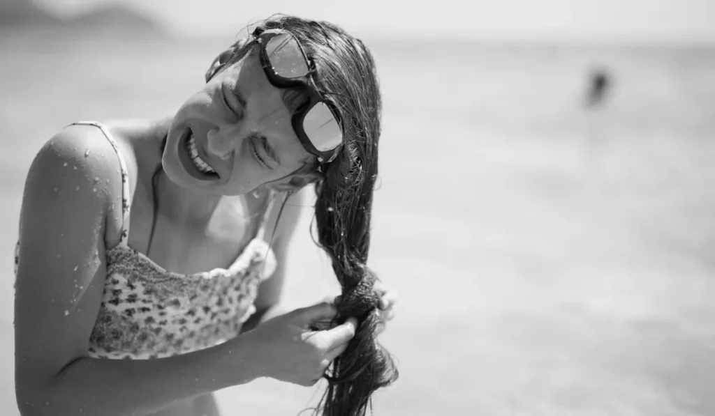 Why Does Salt Water Make Your Hair Feel Sticky? Here's the Science, and What It Means After a Day at a Bali Beach 5 Woman struggling with tangled sticky hair after swimming in the ocean without rinsing off salt water.
