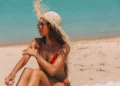 Can You Get Sunburned on a Cloudy Day? A photo of a female tourist sunbathing on a beach in Bali, wearing a straw hat.