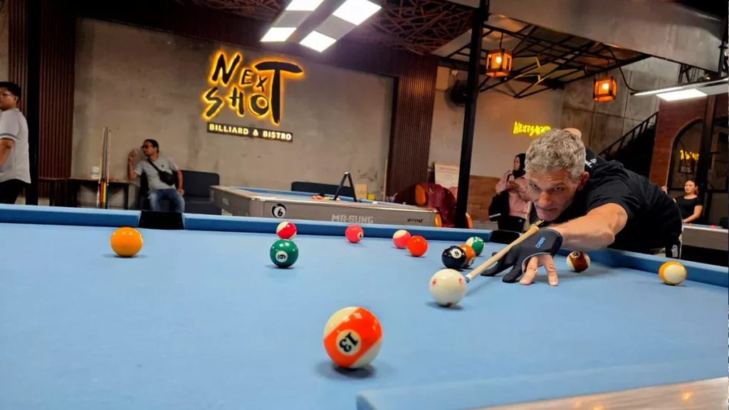 A photo of an American man named Larry playing billiards at Next Shoot Bali (Hey Bali News).