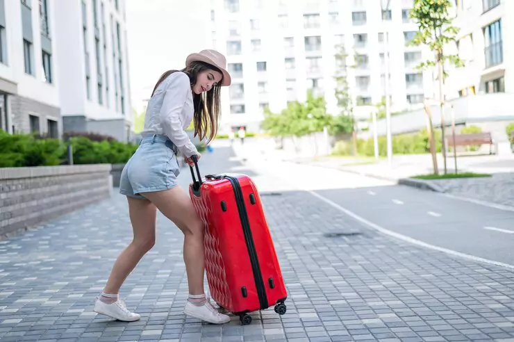 photo of a tourist struggling to carry his luggage
