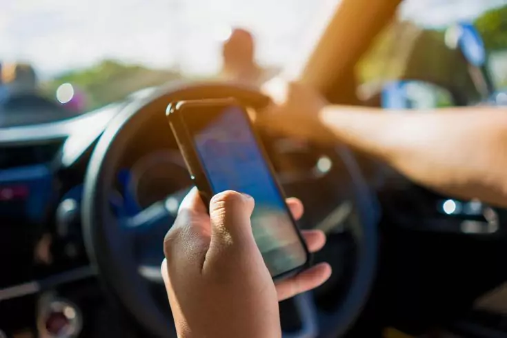 Photo of a car driver looking at google map while holding the steering wheel