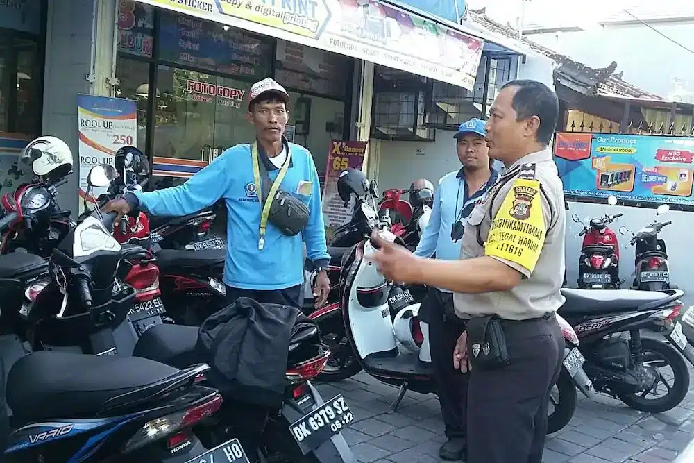 Photo of a parking attendant in Bali being given counseling by a policeman to behave and behave well in front of tourists.