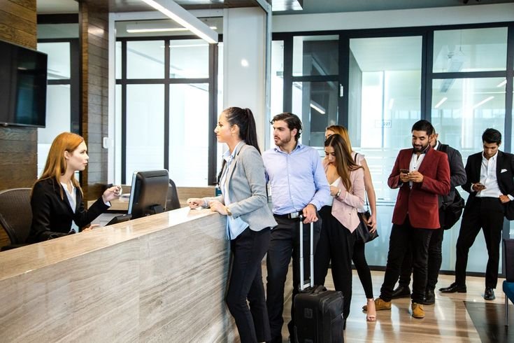 photo of a woman involved in an argument with a hotel receptionist and a long queue of guests wanting to check in.