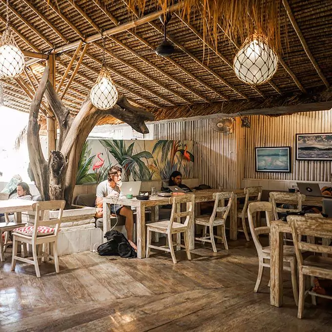 photo in a corner of a cafe in bali showing two tourists focusing on their laptops.. one of the places for digital nomads to work