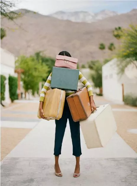 photo of a traveler carrying so much luggage that his face is not visible