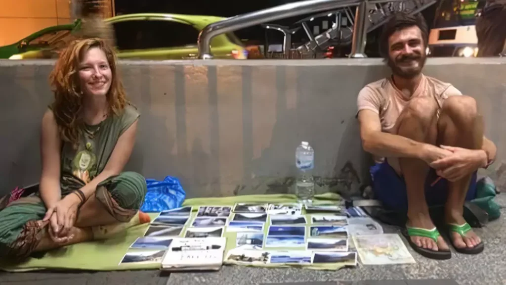 Bali tourist problems - photo of a couple of tourists selling photos on the sidewalk in bali while asking pedestrians to buy their photos because they ran out of money
