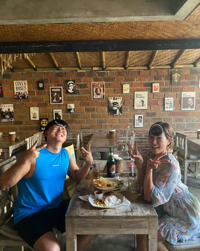 two Japanese tourists laugh out loud enjoying a beer at a cafe in Sanur without worrying about their luggage. - Luggage Storage In Sanur