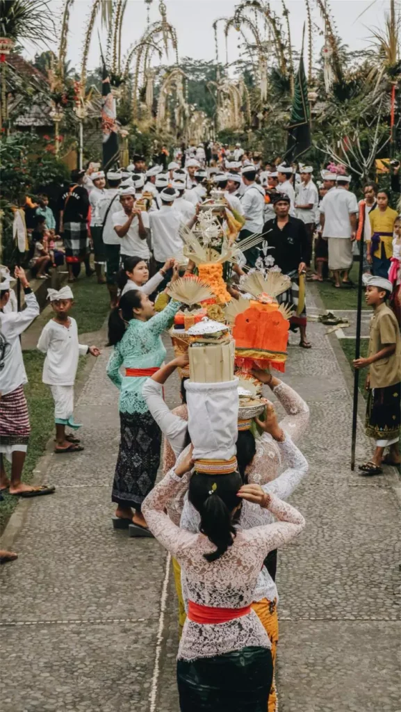 A photo of a festival in the village of Panglipuran, Bali, shows Balinese women parading in traditional dress and carrying offerings.