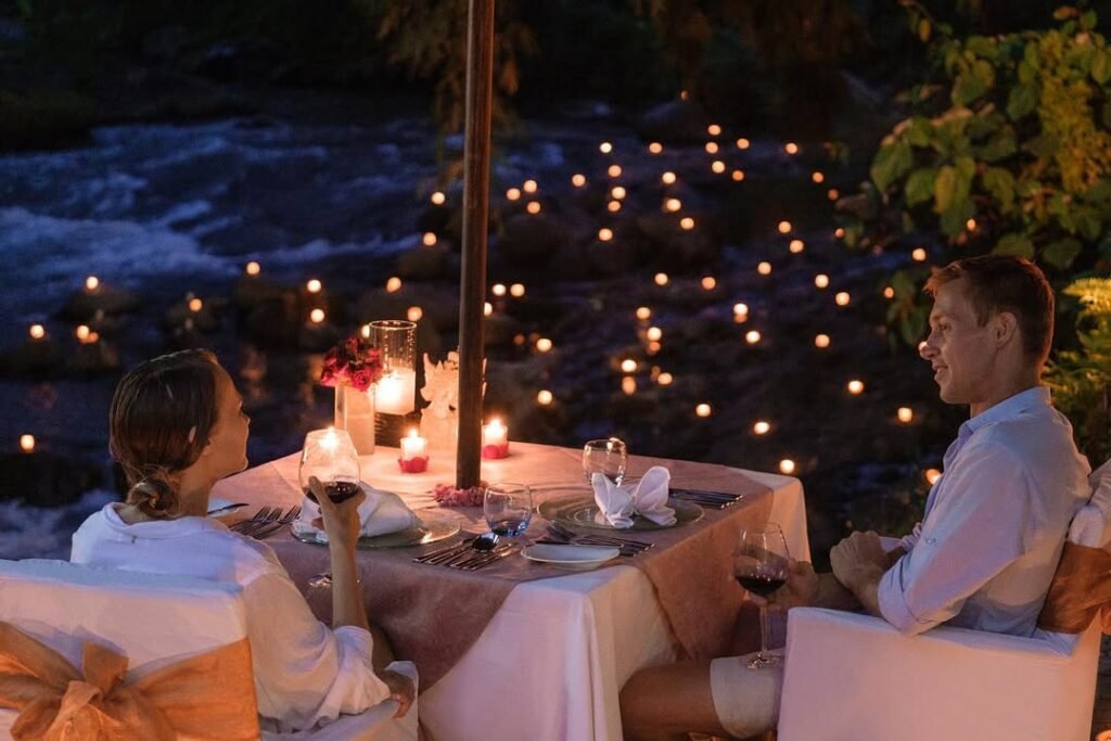 A couple of tourists are having dinner by the river in Ubud, looking romantic with dozens of candles.