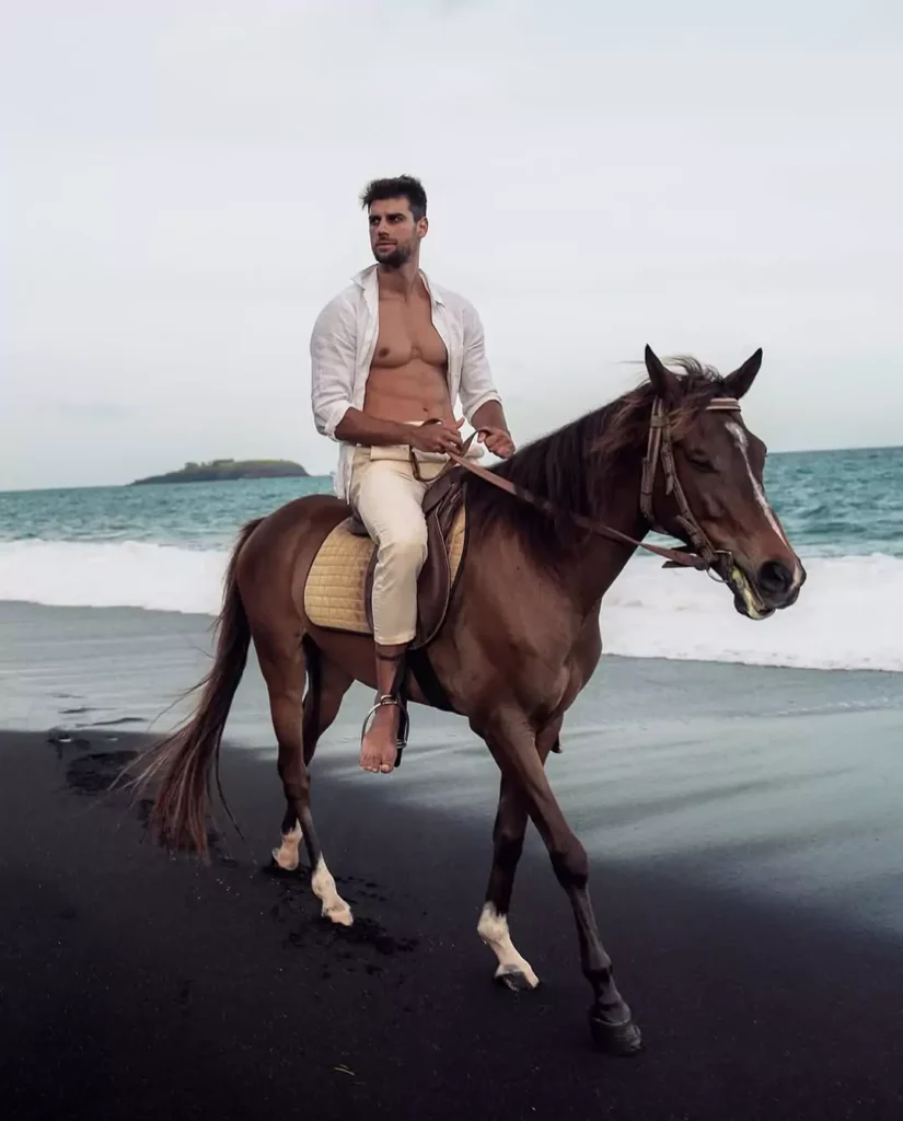 A male tourist is riding a horse on a beach in southern Bali.