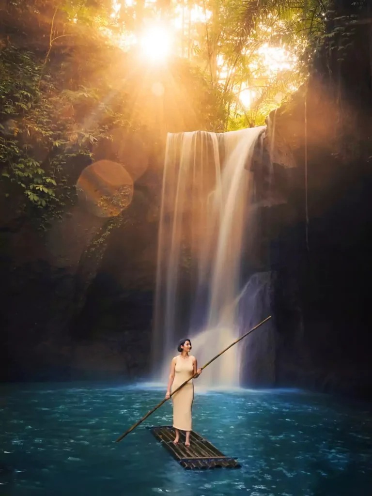 A female guest from Indonesia is standing on a raft at a waterfall in northern Bali.