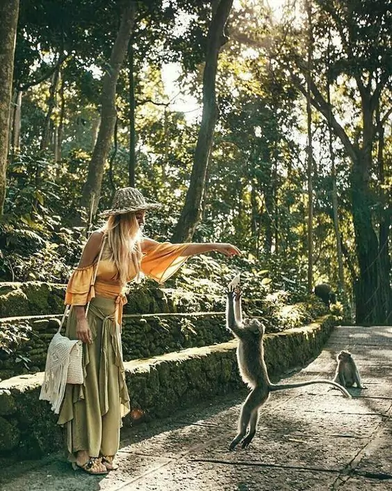 Photo of a woman playing with and feeding monkeys at Monkey Forest Bali Ubud - Bali Day Tours