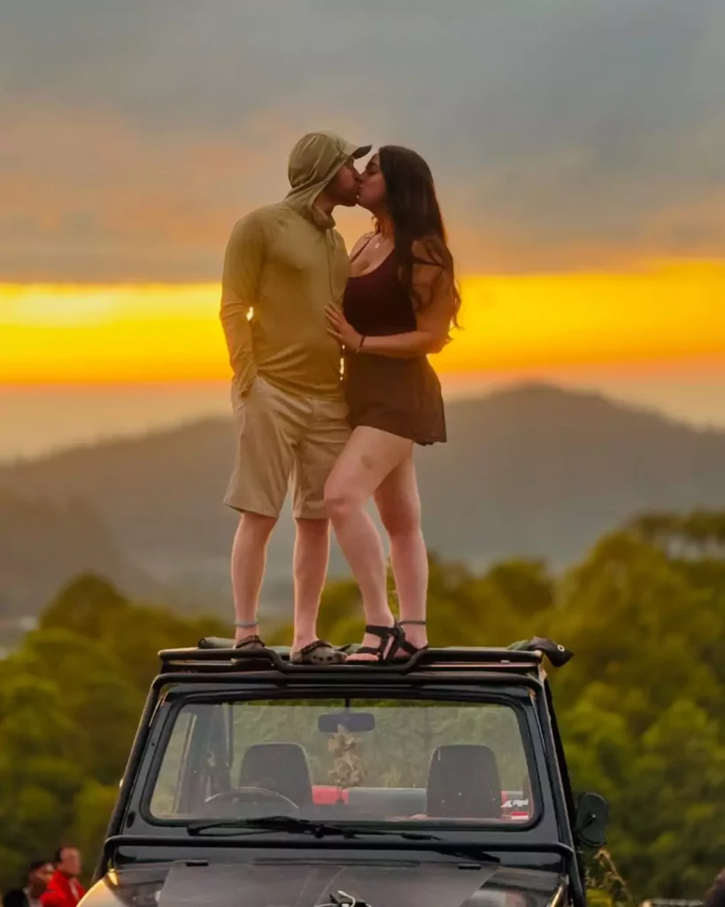 Photo of a couple kissing on top of a car with a sunrise backdrop on Mount Batur