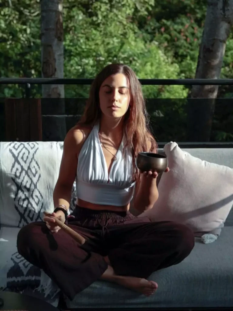 photo of a woman meditating in Ubud with her hands holding a singing bowl