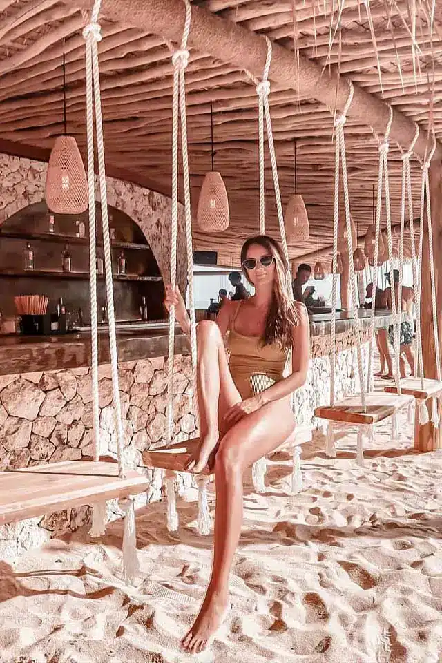 a woman relaxing at a beach club in bali wearing a bikini