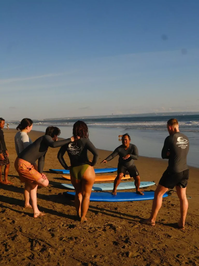 A surfing instructor is giving a briefing and introduction to the basics of surfing on Seminyak Beach, Bali.