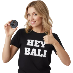 A female tourist from America wearing a T-shirt that says Hey Bali is showing off a free Bali adapter from Hey Bali.