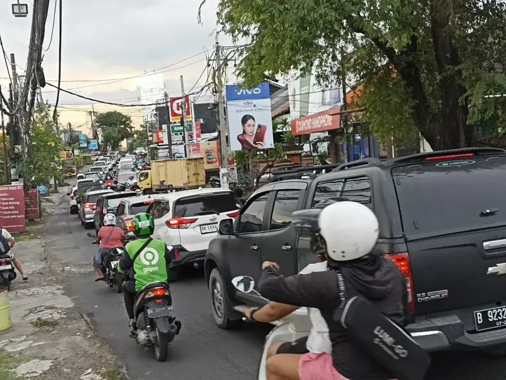 Heavy traffic on the road from Bali Airport to Canggu, showing cars and motorbikes stuck in congestion near Kerobokan area.