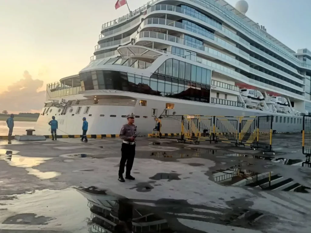 A large cruise ship docked at Benoa Port at sunset, with a security officer overseeing operations, illustrating the arrival point for thousands of travelers seeking transfers.
