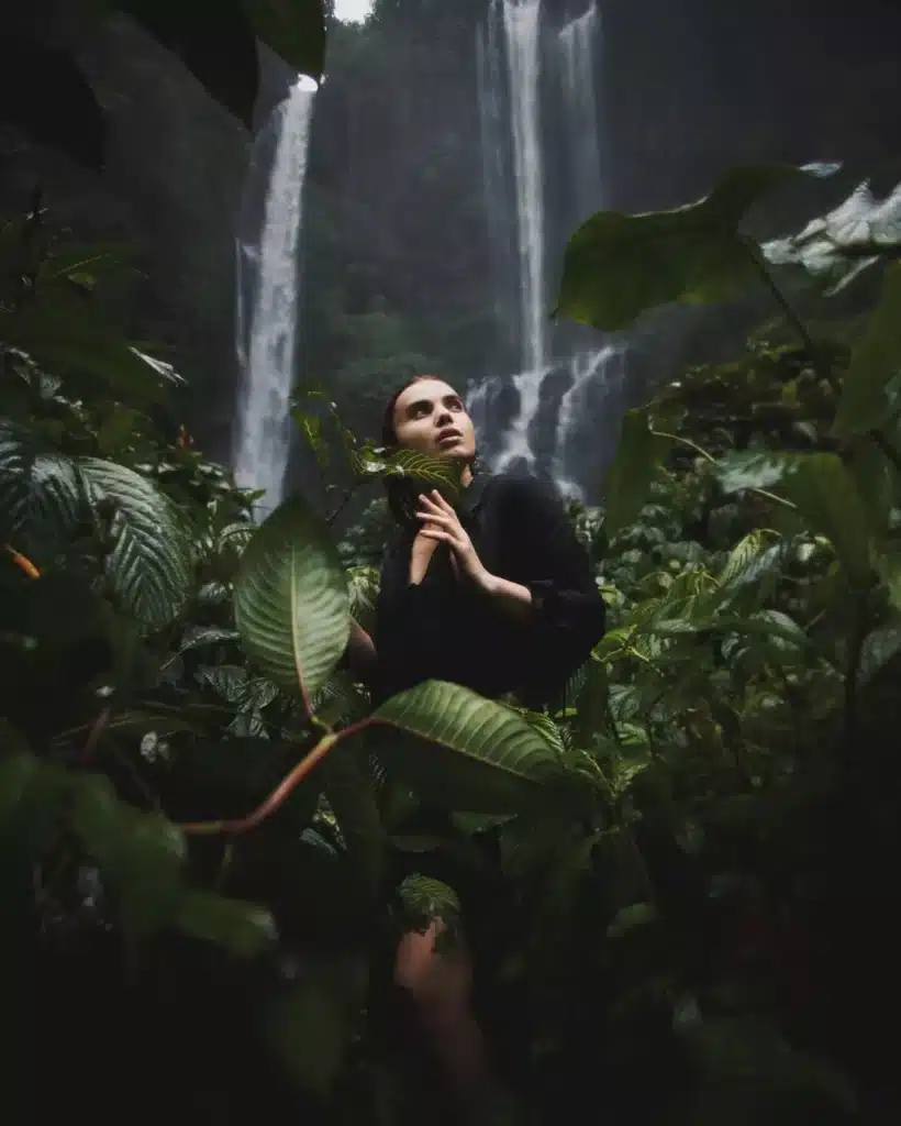 Moody, ethereal image of a woman surrounded by jungle and twin waterfalls in North Bali. This raw, quiet nature is the soul's answer to those who wrongly assume Bali is boring.