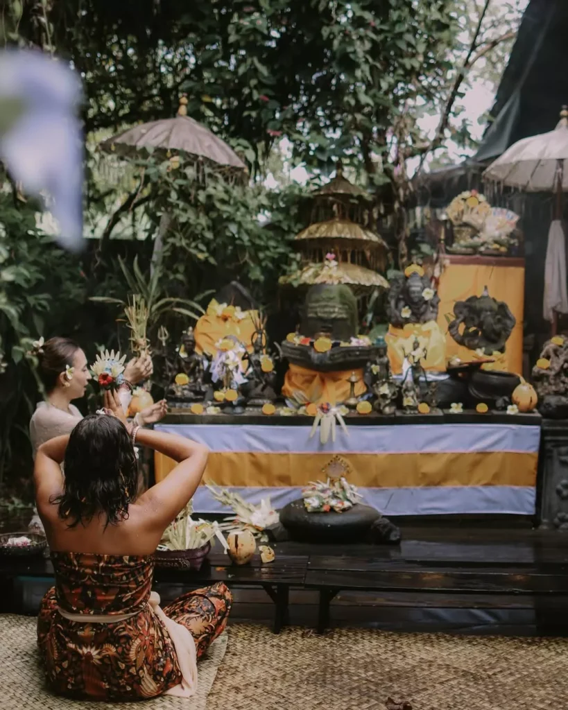 A female tourist is performing a ritual in front of a temple in Bali.